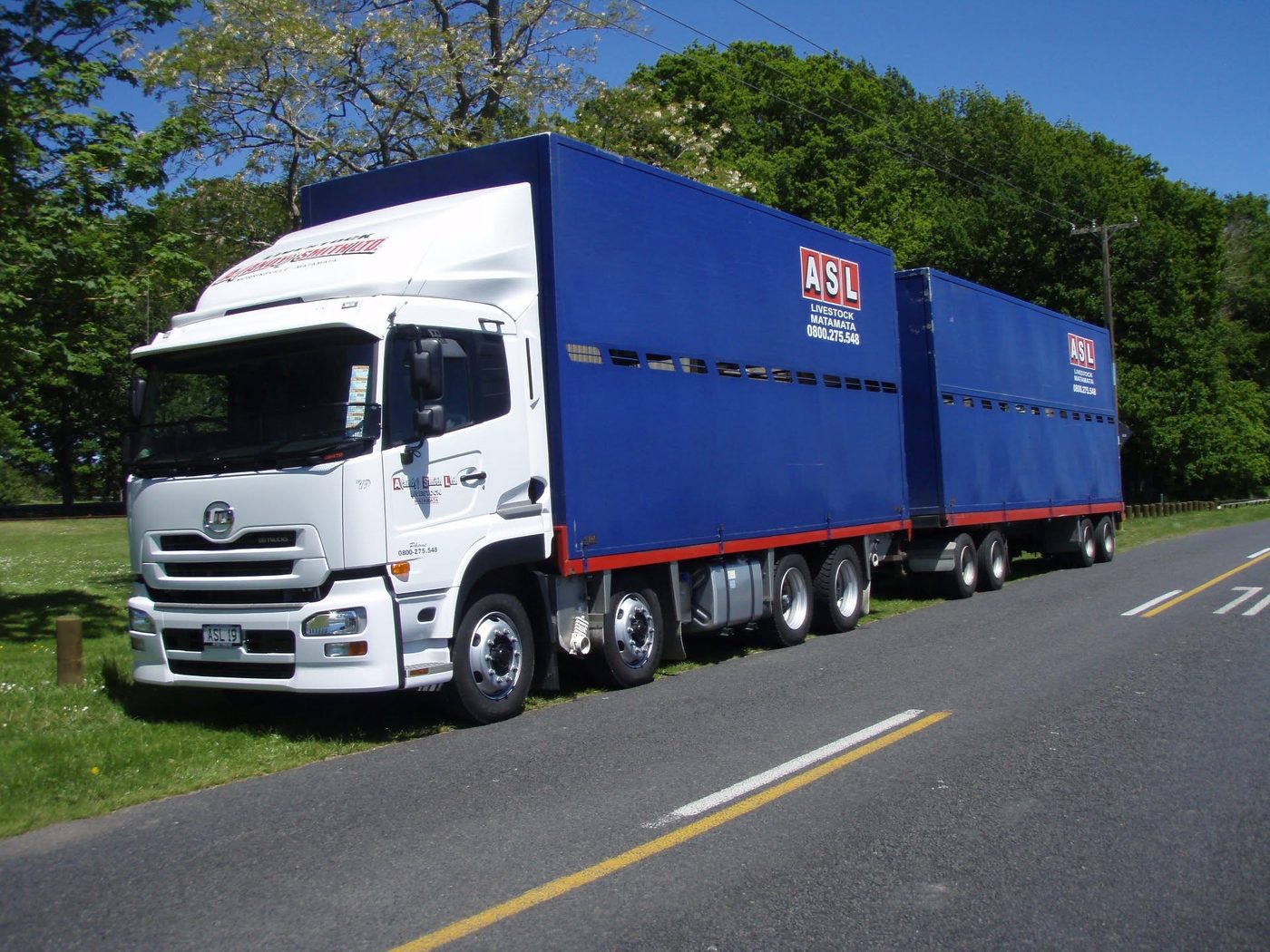 White UD truck with blue ASL Livestock crates parked on a country road